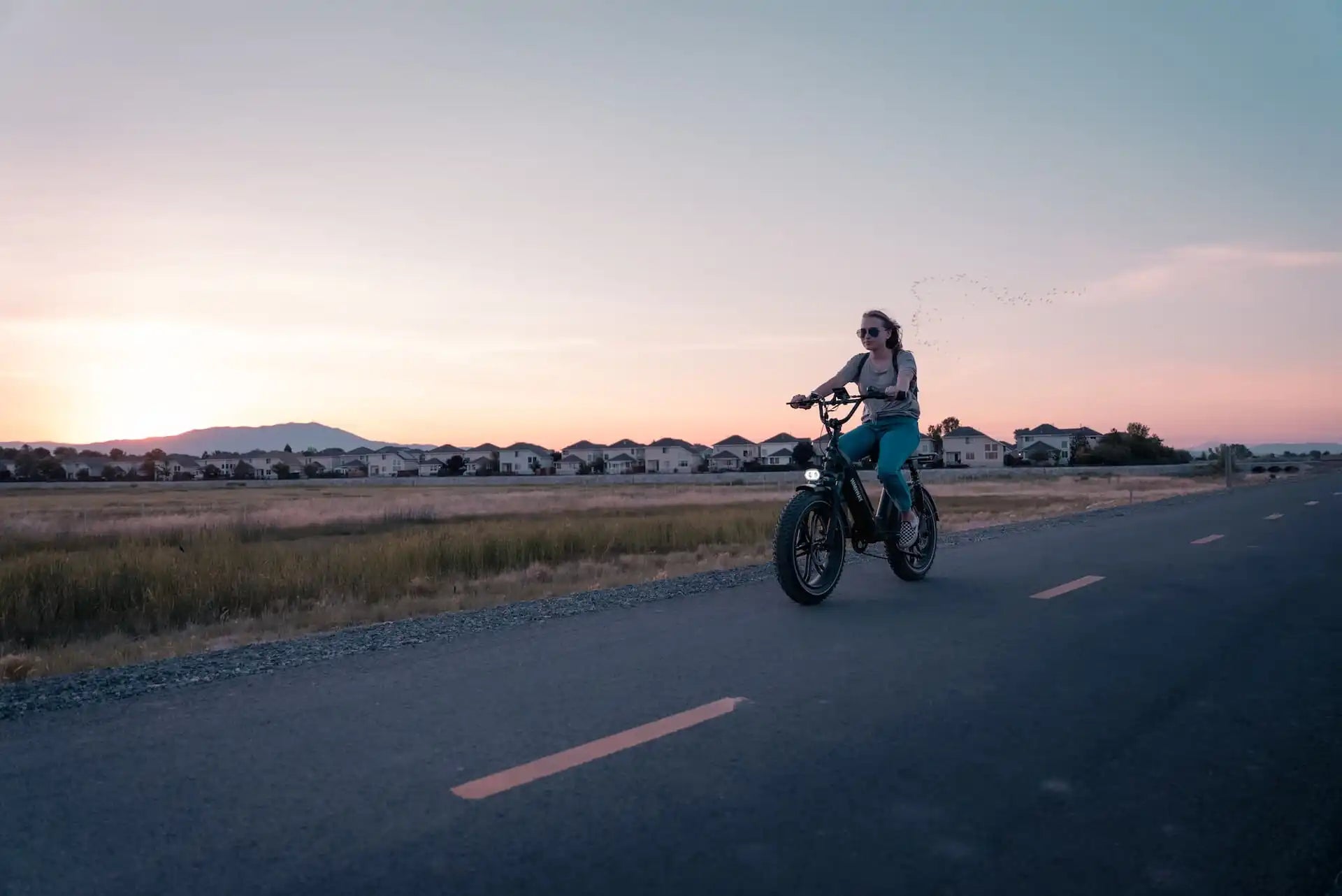 Motorcycle rider cruising on an open road at sunset.